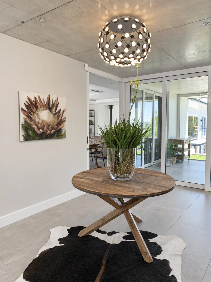 Round timber entrance table, protea artwork and sculptural pendant light